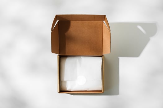 Open cardboard box on a reflective surface with soft shadows photo