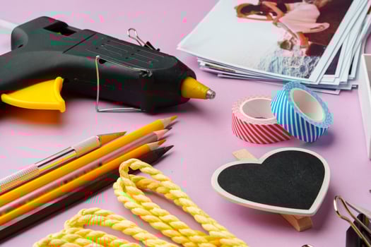 Crafting supplies arranged on a pink background, including glue gun, scissors, and decorative items for DIY projects photo