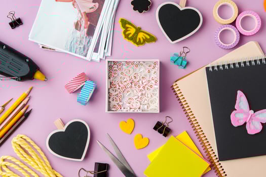 Crafting supplies arranged on a pink background, including glue gun, scissors, and decorative items for DIY projects photo