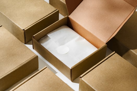 Brown cardboard box with a blank envelope on a light background in a well-lit setting photo
