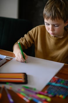 A young boy, with markers in hand, thinks deeply about his next drawing idea. photo