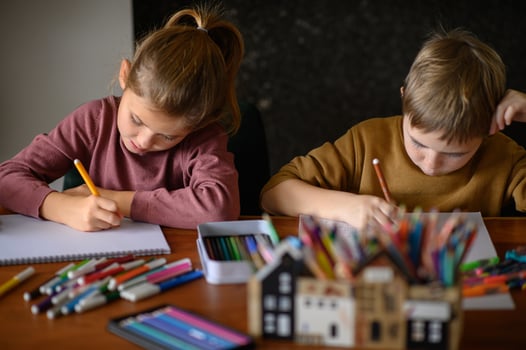 The brother holds a marker while the sister looks at the paper, both deep in thought. photo