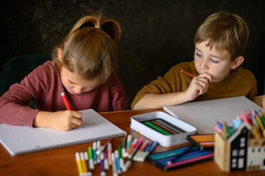 A boy and girl sit together at a desk, imagining their next drawings. photo