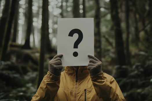 Anonymous person holding question mark sign in foggy forest photo