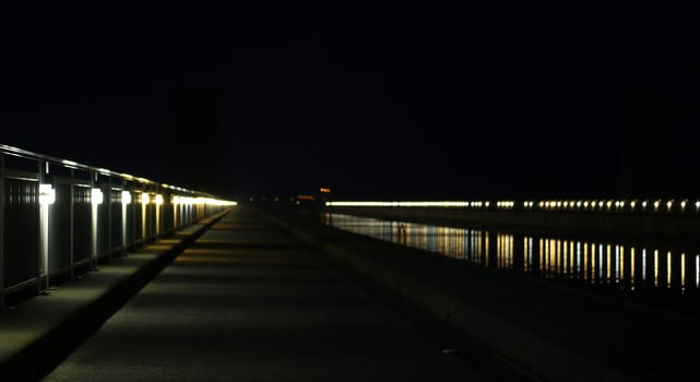 Long row of lights reflected on a river with street. photo