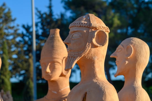 Ancient terracotta figurines displayed against a clear blue sky in a serene garden setting photo
