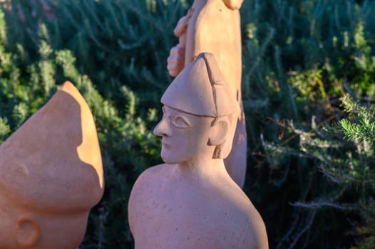 Artistic display of terracotta sculptures in a vibrant garden setting during golden hour photo