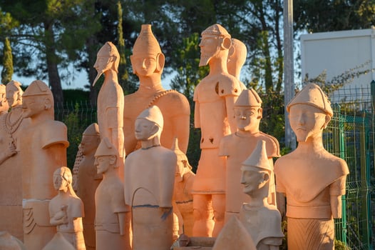 Ancient terracotta figures stand majestically in the evening sunlight among lush greenery photo