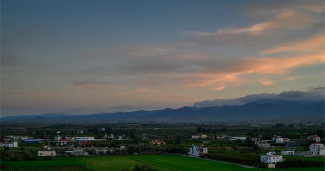 Sunset over serene countryside landscape with mountains and fields in the distance photo