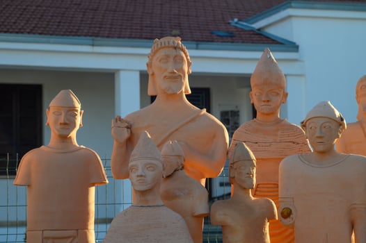 Terracotta sculptures depicting ancient figures in a sunlit outdoor setting photo