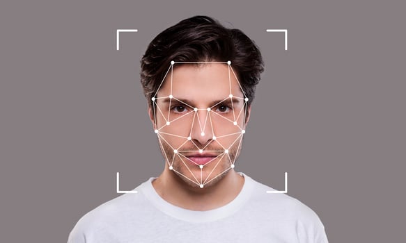 A young man poses against a neutral background while facial recognition technology is applied. The highlights of his facial features are outlined with points and lines, emphasizing identification. photo