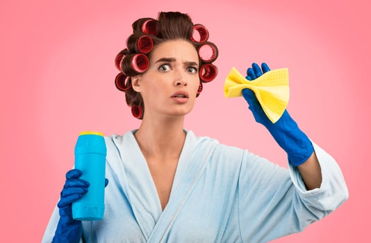 Spring Cleaning. Shocked Glamorous Housewife Holding Detergent Bottle And Sponge Rag Standing Over Yellow Studio Background. photo