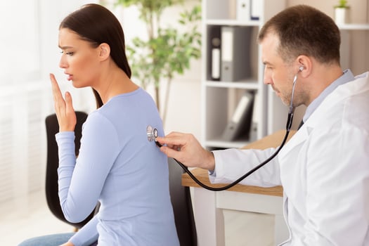Check Up Concept. Mature experienced doctor checking breath of female patient, girl is coughing, side view photo