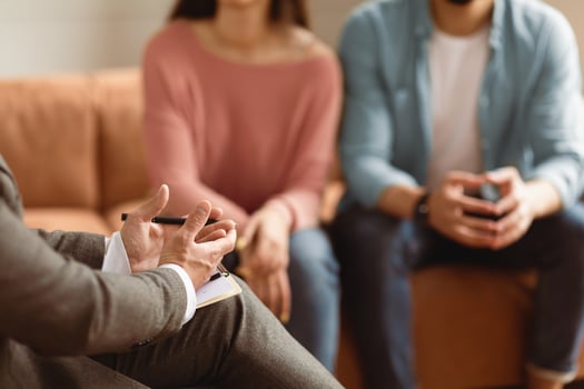 Help Concept. Closeup Cropped View Of Man Counselor Therapist Or Consultant In Suit Talking With Couple Sitting In Office, Giving Professional Advice. Selective Focus On Hands With Clipboard And Pen photo