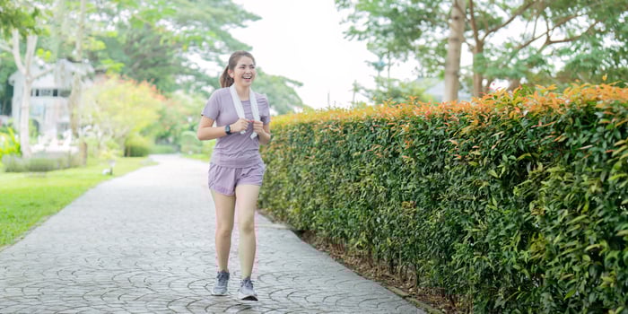 Energetic young woman jogging with a towel in a peaceful park, embracing outdoor fitness photo