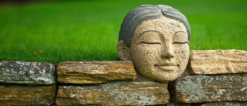 Stone Buddha head statue nestled in a rock wall, serene and peaceful garden decor photo