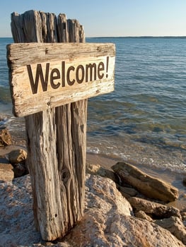 Welcome to paradise. Wooden sign on beach with ocean view photo