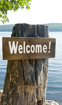 Welcome sign on wooden post by lake photo