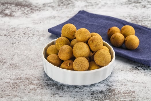 A bowl of kiwis on a table with a blue cloth photo