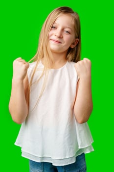 Happy child celebrating success with joyful fist pump in front of bright green background photo