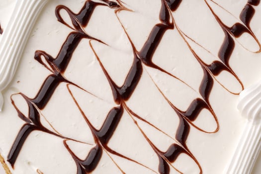 Delicious dessert featuring creamy vanilla ice cream swirled with chocolate sauce and topped with icing photo