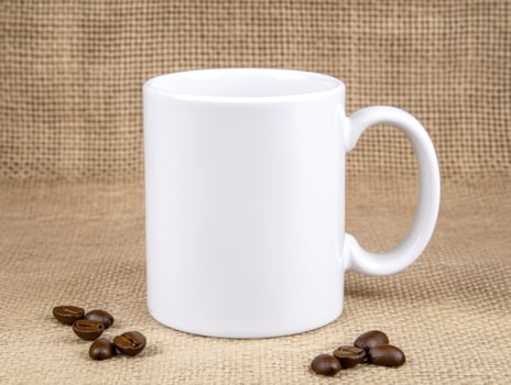 close up of blank white mug surrounded by coffee beans, perfect for showcasing designs or branding. rustic background adds warmth to scene photo