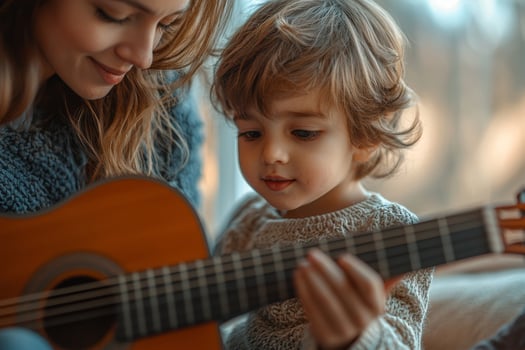 A mother teaches her young son to play guitar on a cozy afternoon at home, sharing a moment of musical bonding and joy photo