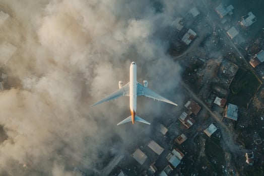 Aerial view of an airplane flying above a city enveloped in clouds during golden hour showcasing vibrant colors and urban landscape photo