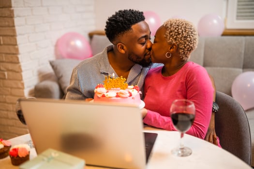 Boyfriend and girlfriend kissing while holding birthday cake photo