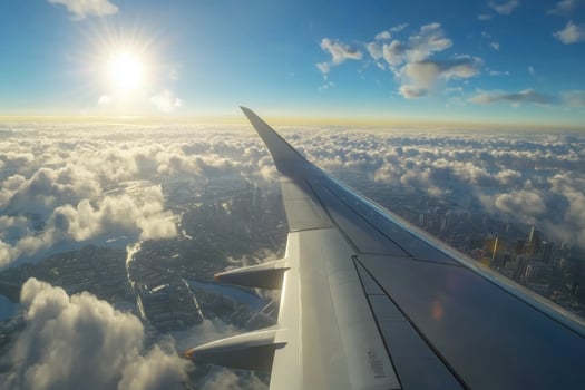Captivating view from airplane wing soaring above clouds at sunset over city landscape photo