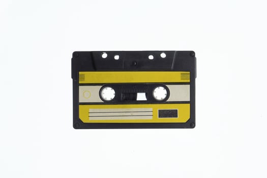 A vintage audio cassette tape with an yellow and black label, isolated on a white background, evokes nostalgia and retro vibes. photo