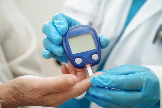Asian doctor using digital glucose meter for check sample blood sugar level to treatment photo
