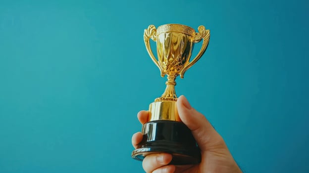 person holding golden trophy against blue background, symbolizing achievement and success photo