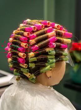 In a hairdresser's, a girl is curling hair with curlers. A close-up of the client's hair and head is shown. All hair is completely curled. photo