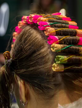 In a beauty salon, a girl is getting her hair permed. Close-up of the curlers. The girl is getting wavy curly hair. One row of curlers photo