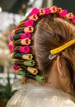 A girl in a hairdresser's is curling her hair with curlers. A close-up of the client's hair and head is shown. The curlers are laid in one row. photo