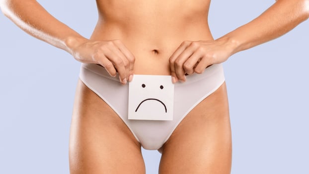 Intimate Female Health Problem. Closeup Cropped View Of Unrecognizable Lady Holding Paper Card Note With Sad Smiley Face Near Her Belly, Wearing White Lingerie. Digestive Disorders, Period Pain Issues photo