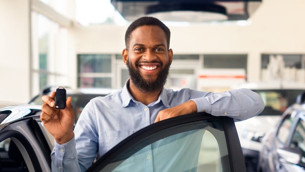 Happy Owner. Joyful Black Man Standing Near Luxury Vehicle And Holding Keys, Cheerful African American Male Posing In Modern Dealership Center After Purchasing New Automobile, Copy Space photo