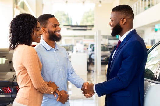 Sales Manager Helping Black Couple Choose New Car In Modern Dealership Center, Shaking Hands After Successful Deal, African American Spouses Buying Family Vehicle In Auto Showroom, Closeup photo