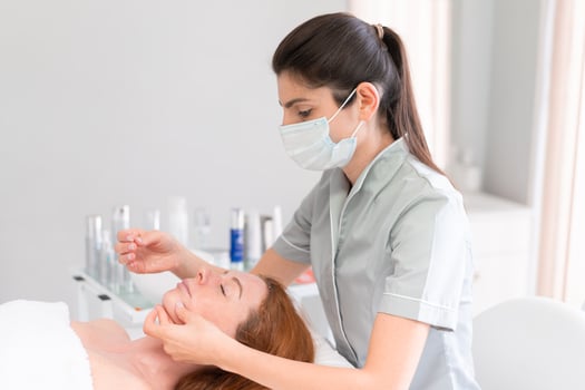 Massage therapist massaging woman's face at cosmetology clinic photo