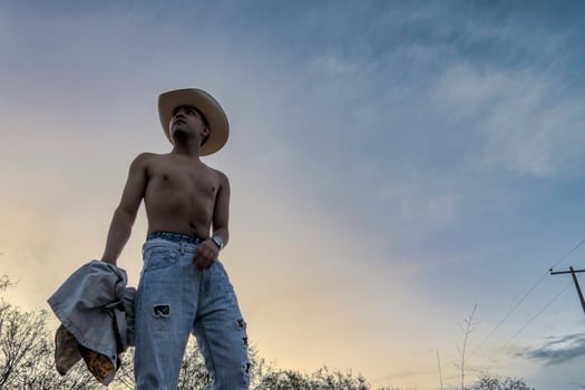 Mexican Cowboy standing confidently against a colorful sunset sky in rural Mexico photo