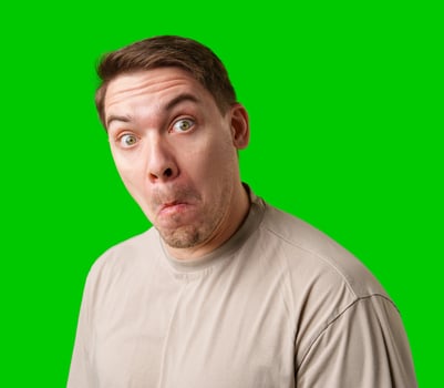 A surprised man stands in front of a bright green screen, expressing shock with his mouth open photo