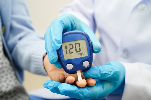 Asian doctor using digital glucose meter for check sample blood sugar level photo