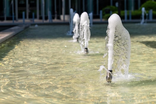 Water fountains create playful displays with bubbles at a modern urban location during sunny day photo