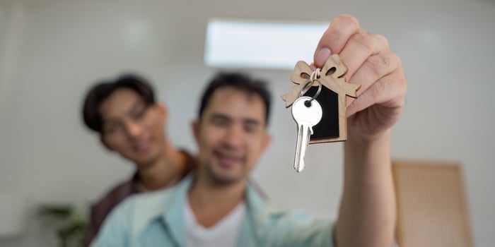 Gay couple proudly holding keys to their new home, celebrating their new beginning photo