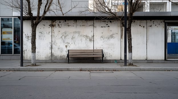 Empty urban bench by a wall with trees in a quiet street setting during daytime photo