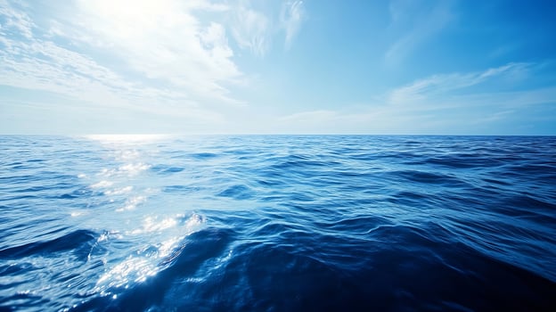 Vast Aerial View of Tranquil Blue Ocean Under Clear Sky with Sunlight Reflection photo