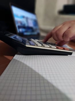 Person calculating on scientific calculator with graph paper on desk photo
