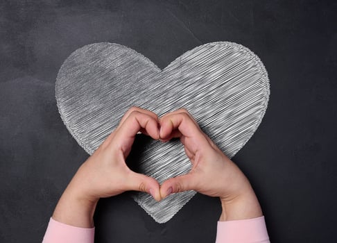 Heart drawn with white chalk on black board and female hands, concept of kindness love and donation photo