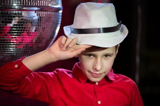 A little boy in a classic hat against the background of a shiny disco ball. photo